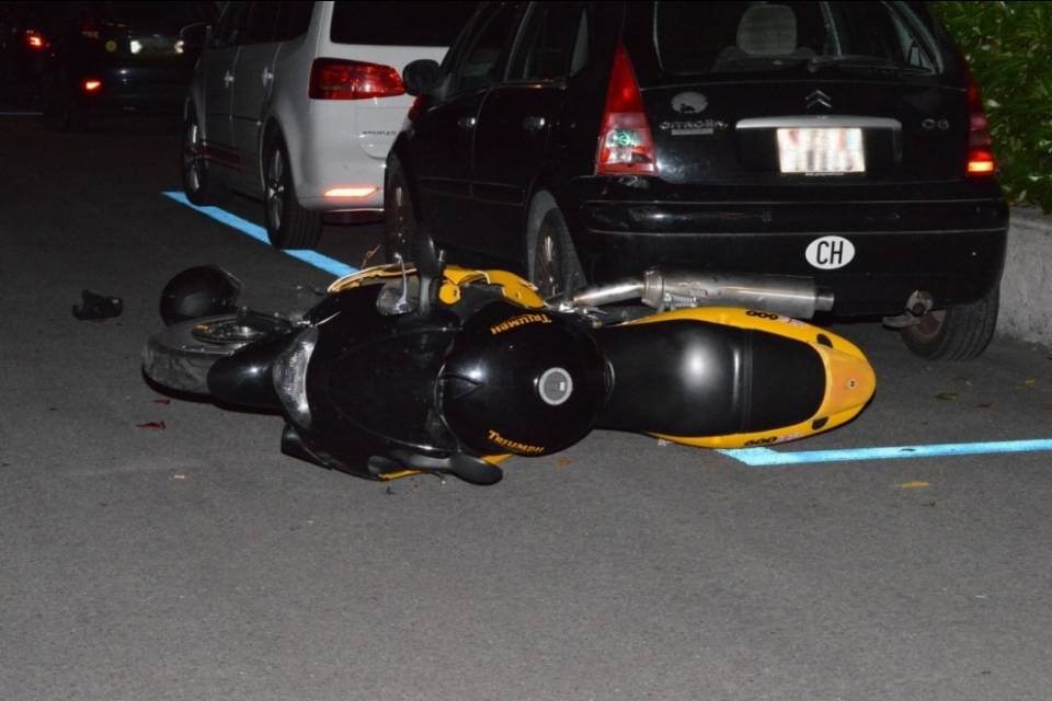 Motociclista urta un'auto parcheggiata e poi si allontana