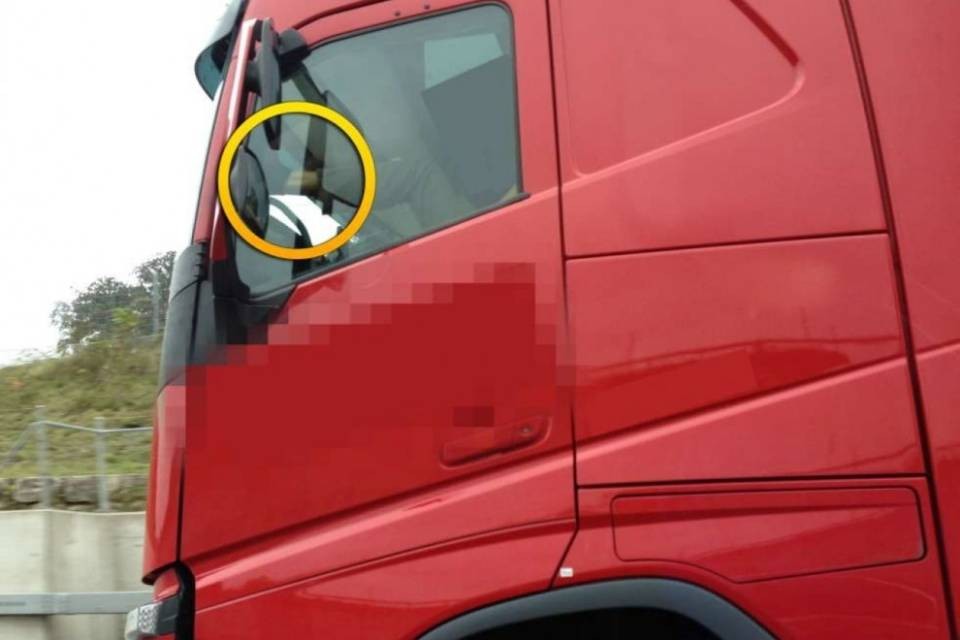 Camionista guida con una gamba sopra il cruscotto